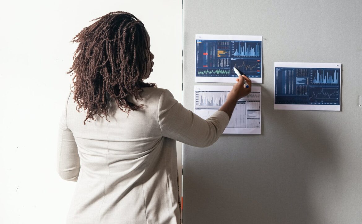 photo of a woman with curly hair pointing at a paper with a graph