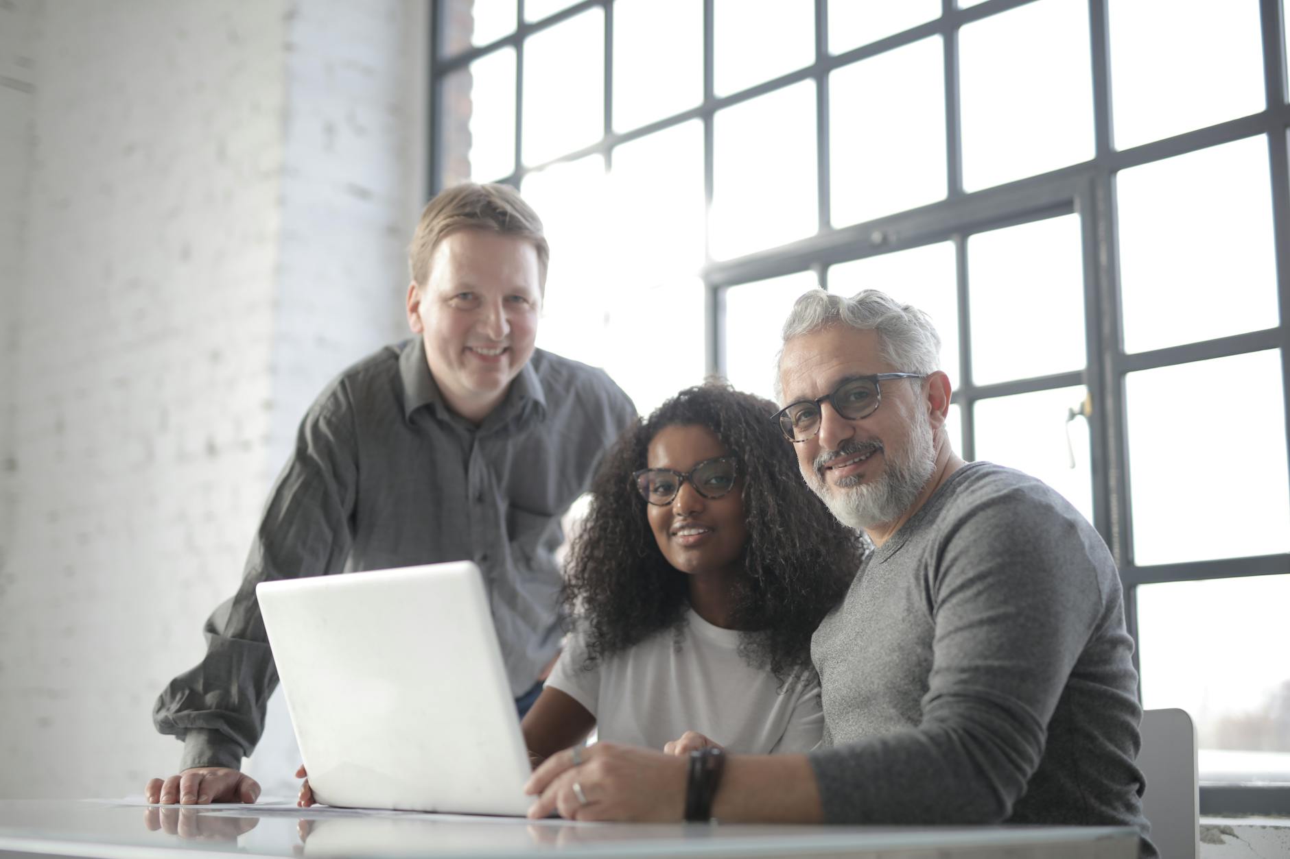 smiling multiracial coworkers working on laptop in modern workspace